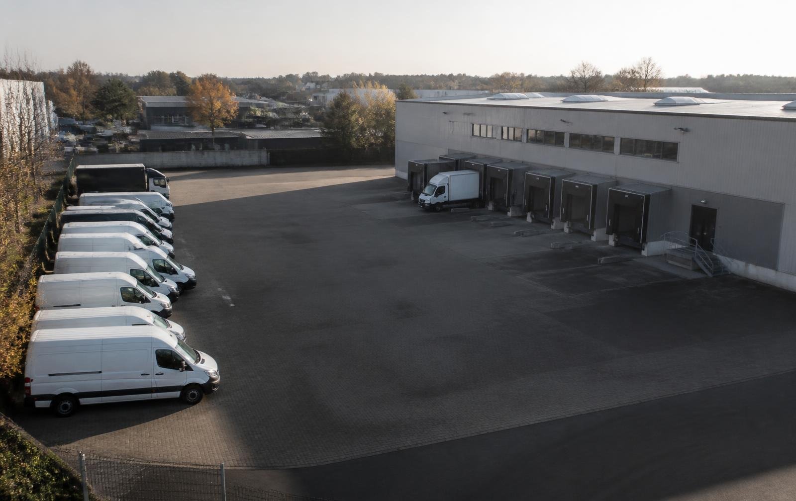 Company depot yard with commercial vans beside a warehouse with loading bays