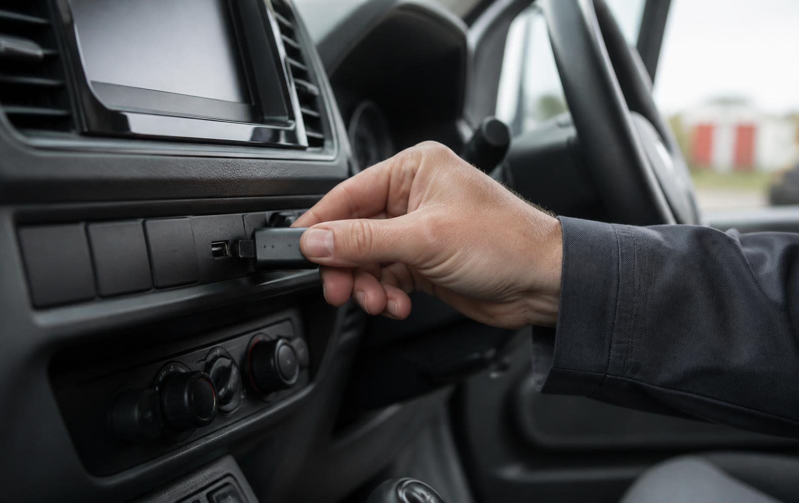 Hand plugging a small Asset On Site USB tag into the USB socket of a commercial van